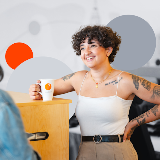 Smiling woman with curly hair and tattoos holding coffee mug with Quadient logo in modern office