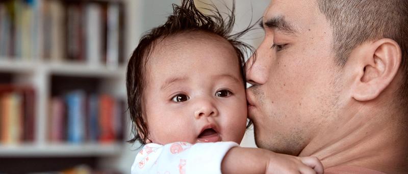 Pai segurando a criança no colo e beijando sua bochecha