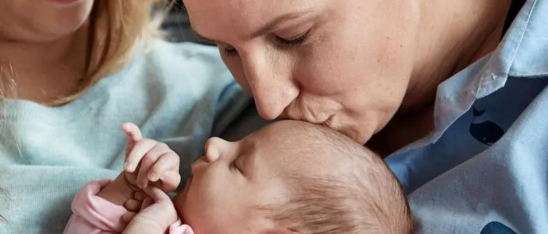 Mulher beijando a cabeça do bebê