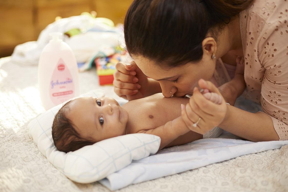 Mãe beijando bebê deitado nunma toalhinha