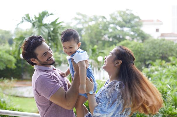 Casal sorridente com bebê num local cercado por natureza