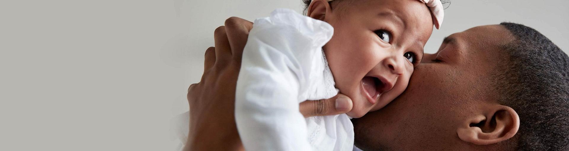 Pai beijando a bebê sorridente 