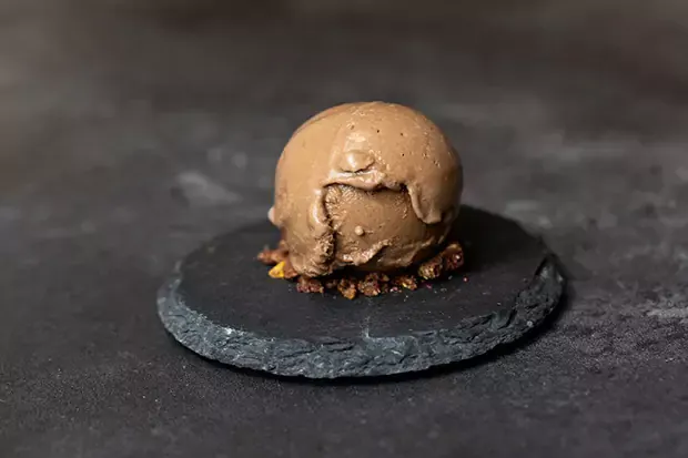 A scoop of cashew based cocoa ice cream served on a stone plate