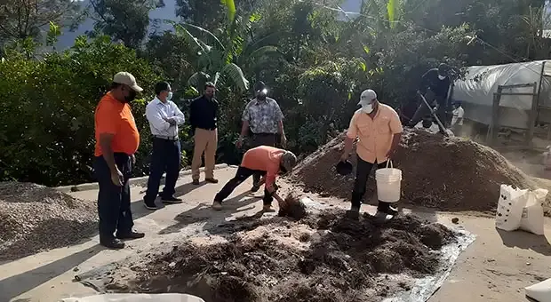A group of workers going through a pile of soil