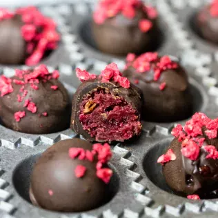 A bitten chocolate ball filled with fruit