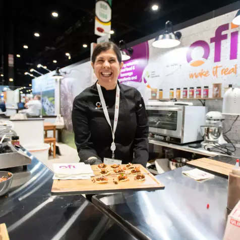 Woman hapily serving food at ofi booth
