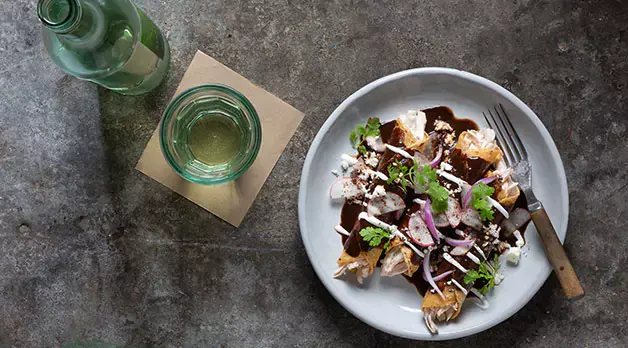 Plate with three chicken wraps, drizzled with a special dressing and a beverage on the side