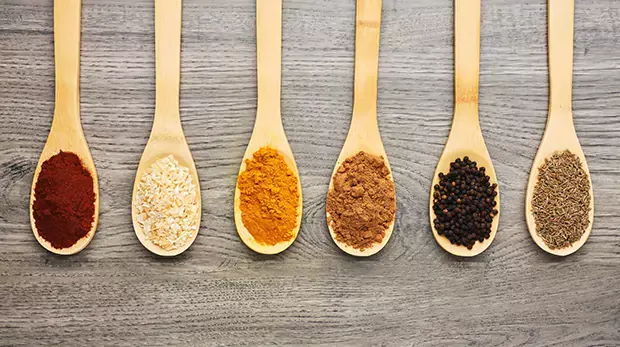 Top view shot of six wooden spoons filled with various spices