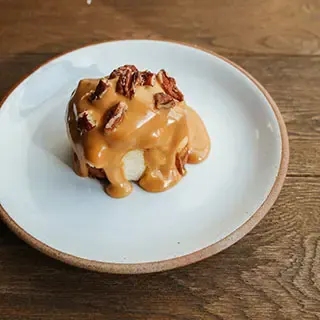 Dessert covered in a sauce, topped with crushed nuts
