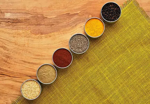 Set of spices lined up in a row on a wooden table