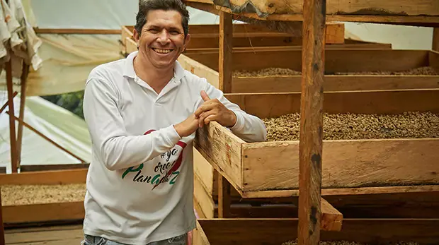 Smiling man leaning against wooden cultivation beds