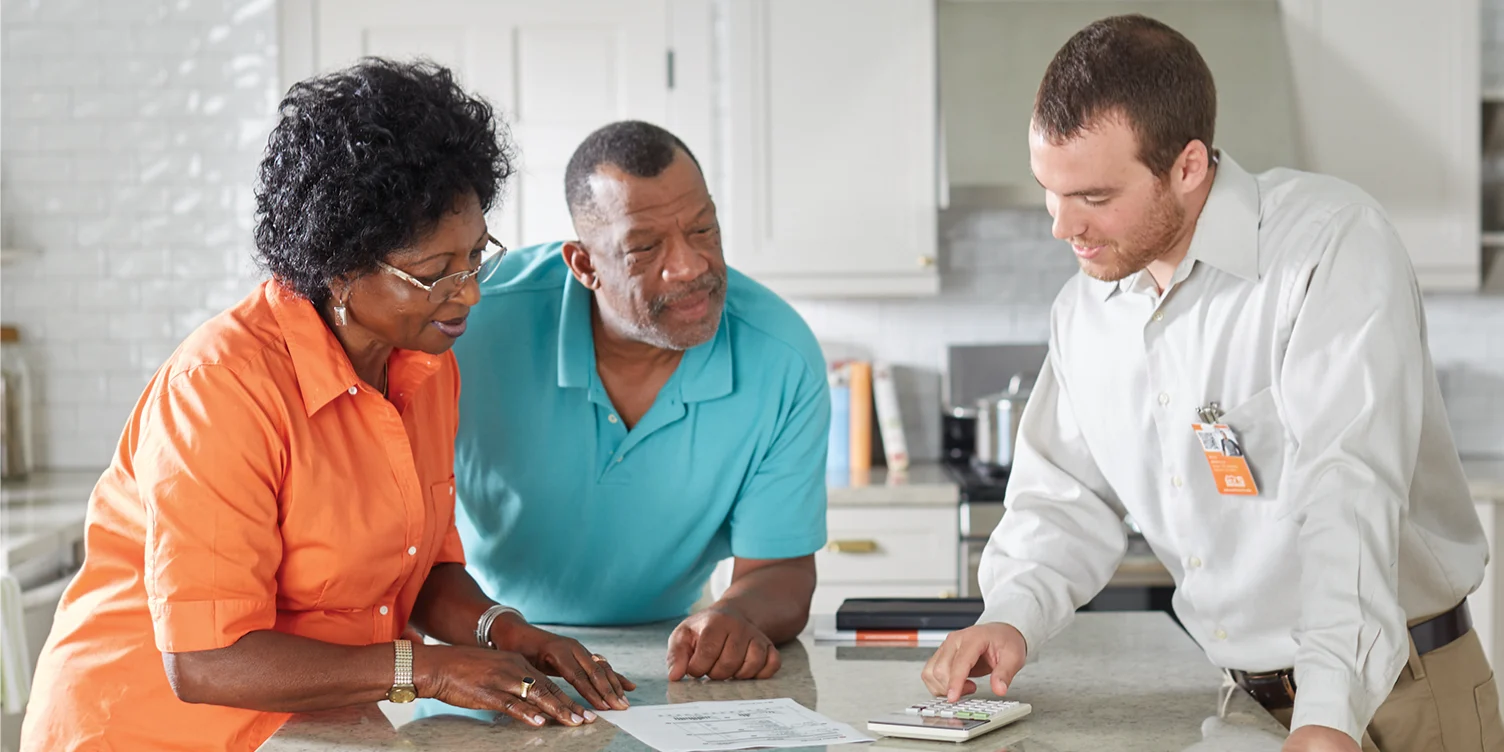 Home Depot pro and two people stand around a kitchen island talking.