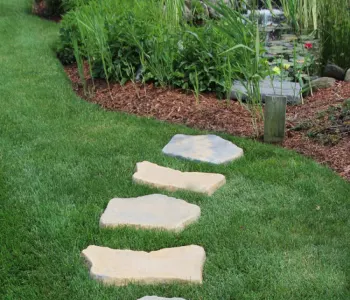 Stone garden path on lush green grass; orange tile icon