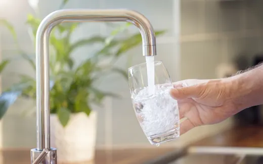 A person filling a glass of clean drinking water