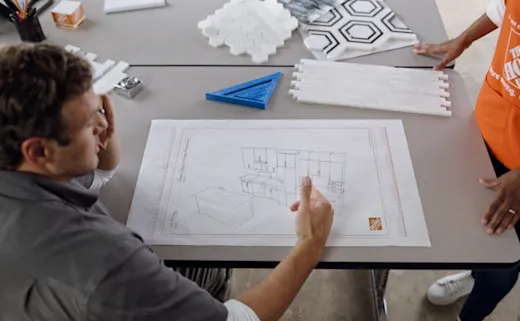 Designer drafts kitchen design plans sitting at a table.