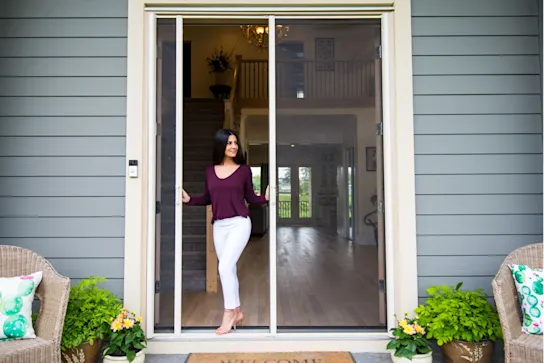 a woman opening a white screen door