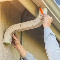Service pro installing rain gutters; orange tools icon