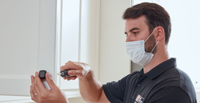 a Home Depot cabinet installer screwing in black cabinet hardware