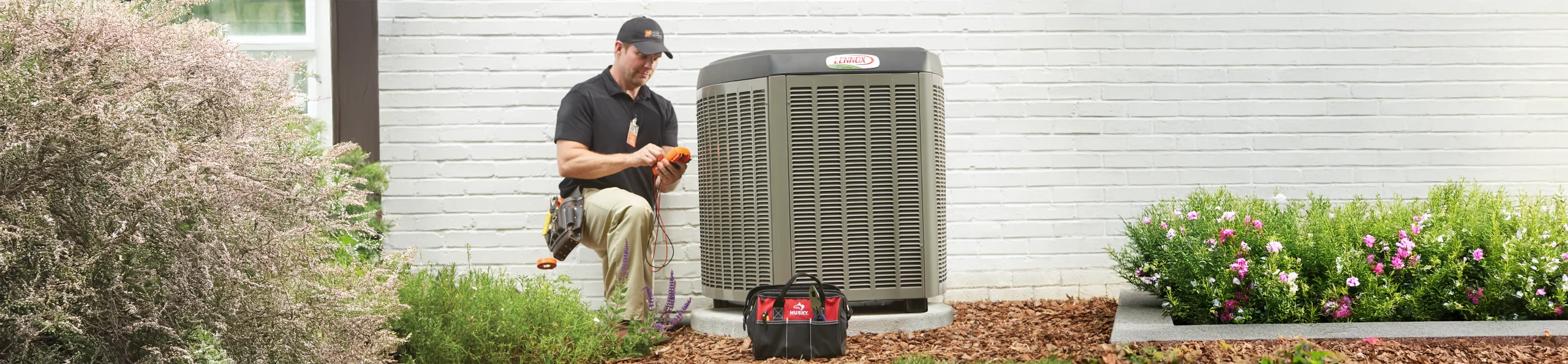 HD Service pro repairing an HVAC unit outside of a customer's home
