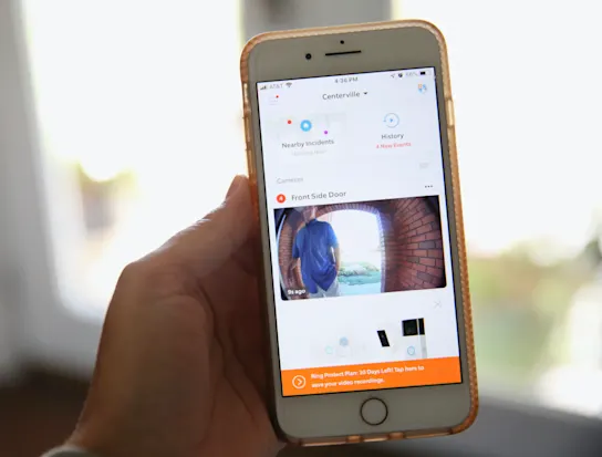 A person holding a smart phone view their doorbell surveillance footage