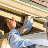 Service pro repairing a leaky gutter; orange tool box icon