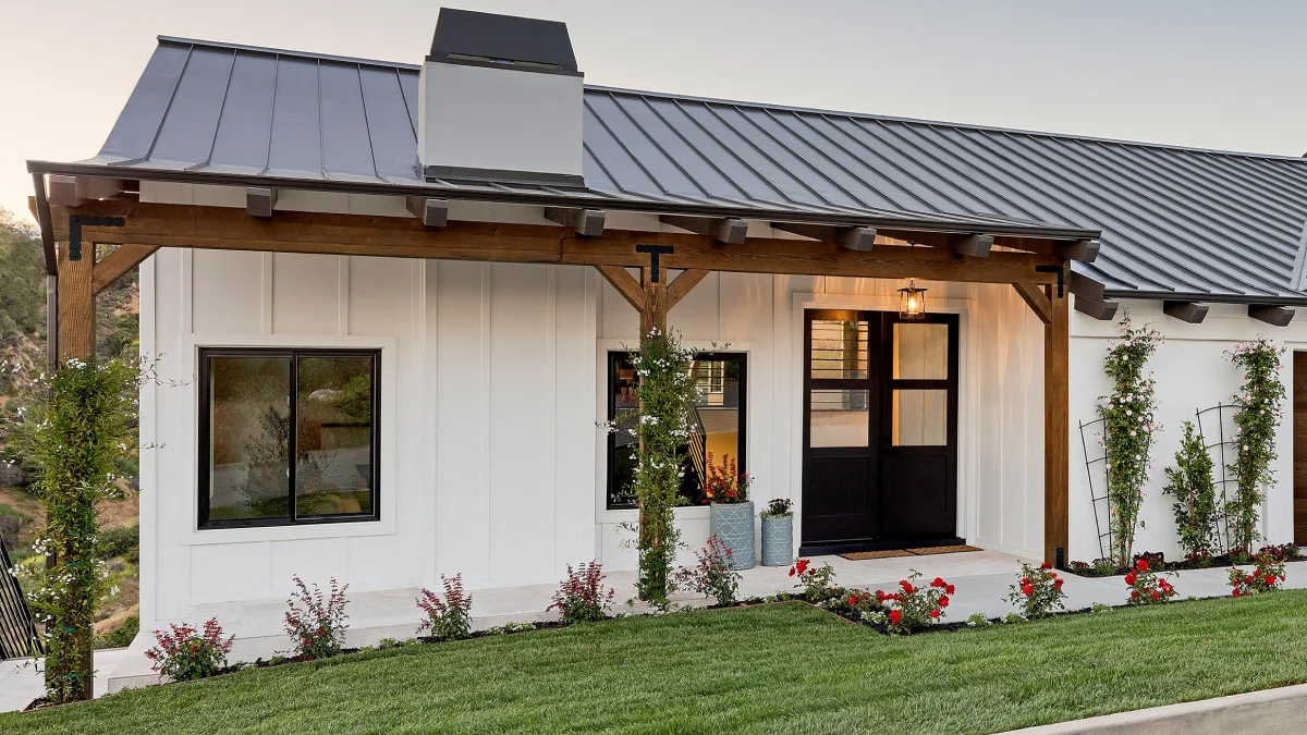 A modern home with black framed windows, black double doors, and a white exterior