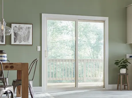 White patio screen door in a green kitchen and dining room.
