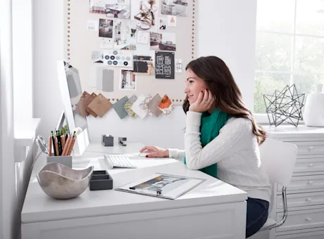 Designing a kitchen online with woman at computer desk shown