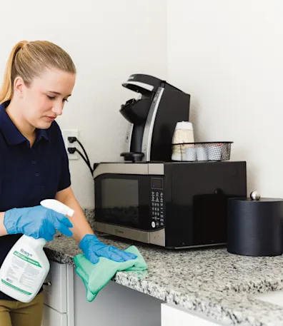 A woman cleaning a solid surface countertop