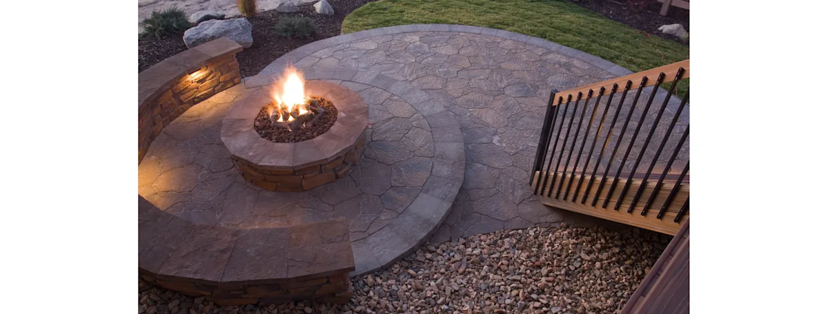 A backyard stamped concrete fire pit seating area