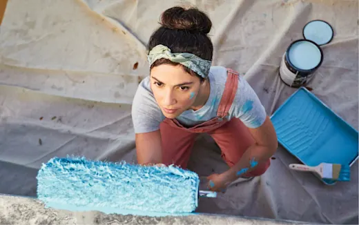 A woman painting the exterior of her home after a window and door installation.