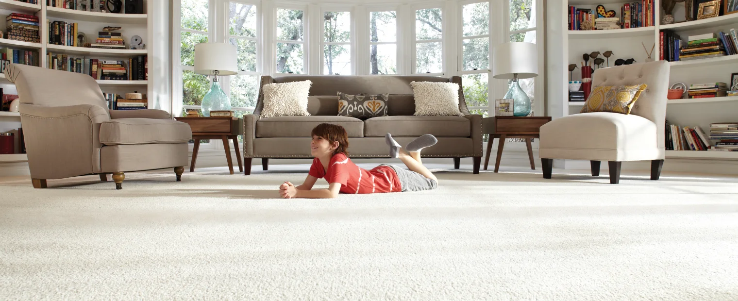 Little boy laying down on the large white Lifeproof carpet in a grand living room