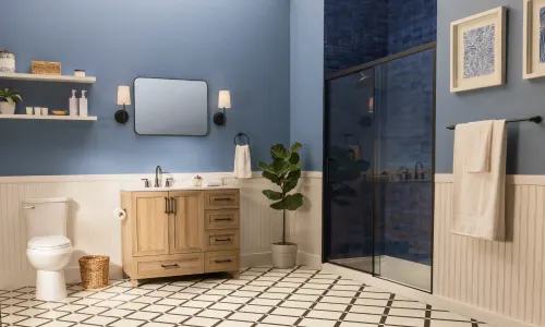 Modern bathroom with glass shower, blue walls, and cream colored wood paneling; orange bathroom icon
