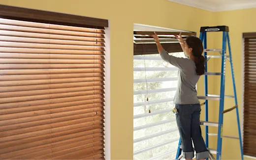 A women removing wooden blinds preparing for a new window installation.