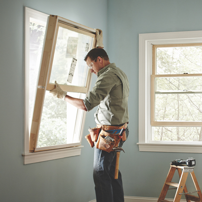 A Home Services window contractor installing a wood window