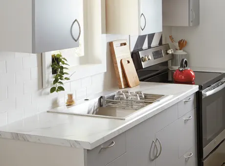 White laminate countertops with a kitchen sink and a stove. 