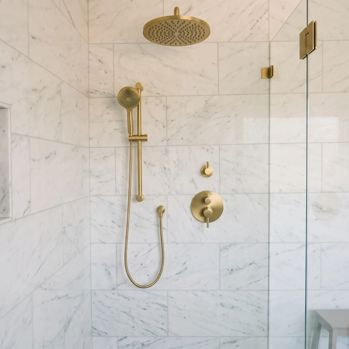 The interior of a walk-in shower with gold hardware and fixtures