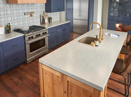 A kitchen with blue cabinets and grey solid surface countertops.