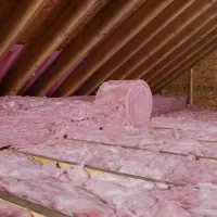 Fluffy pink insulation in an attic; orange checklist icon