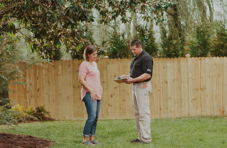 Woman and man standing in front of an installed fence in yard