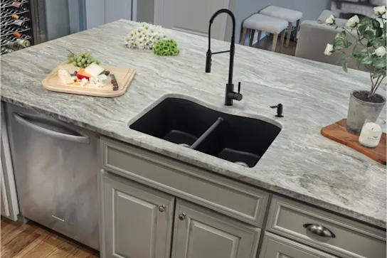 A black quartz composite sink in a kitchen island
