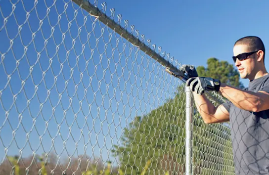 Man in sunglasses install chain link fence