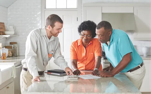 A couple receiving an HVAC consultation in their kitchen