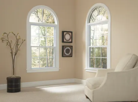 Two shaped windows with white frames in a living room