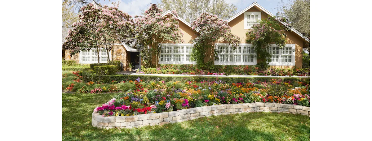A charming home with a new decorative block wall filled with colorful flowers
