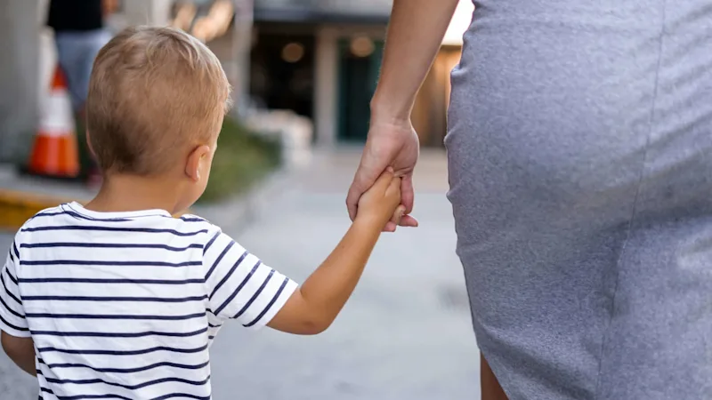 A parent and young child walking hand-in-hand, representing future security.