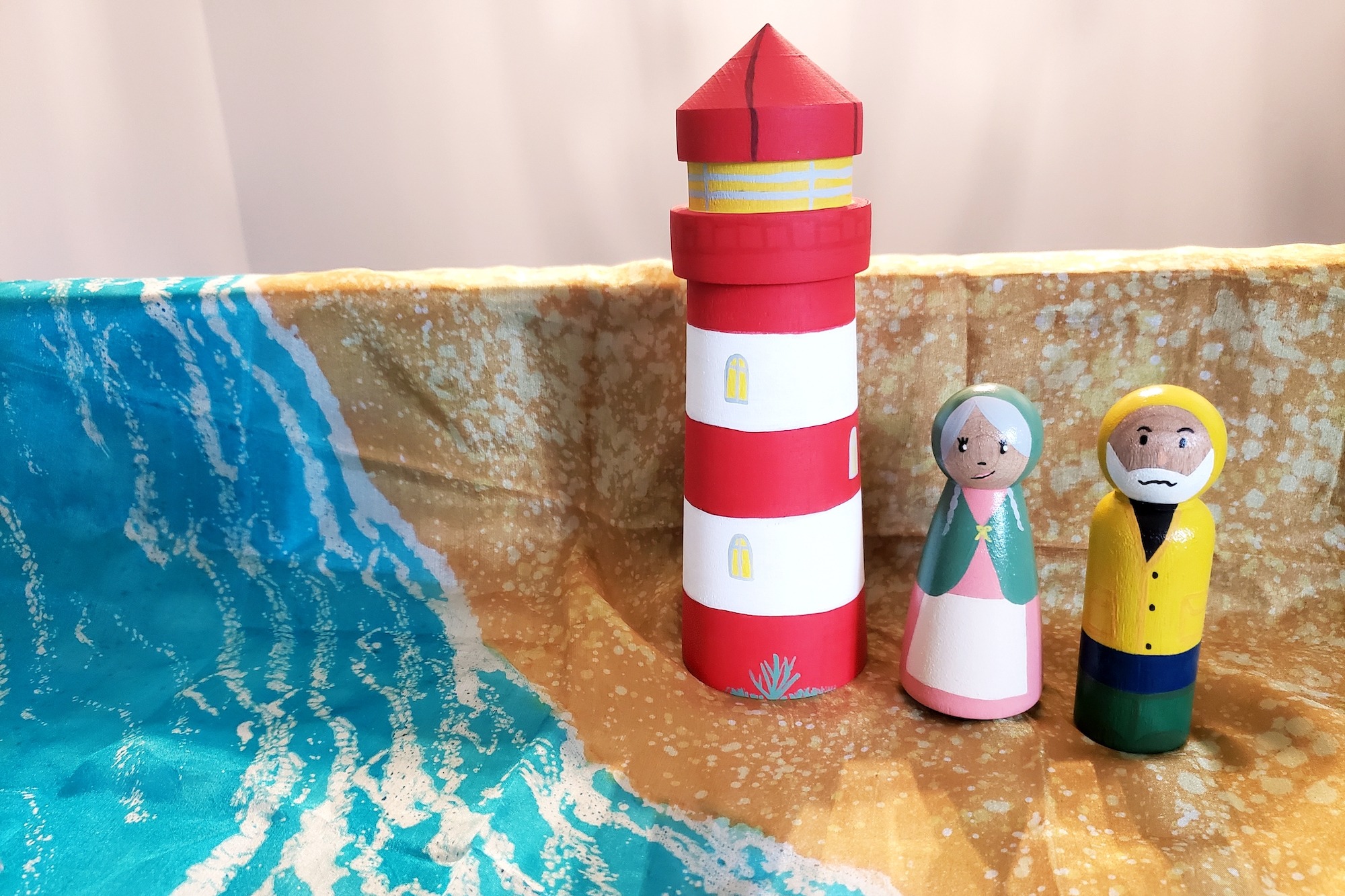 A lighthouse keeper and his wife next to a lighthouse on a beach.