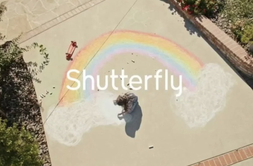 Child using chalk to make a rainbow on a cement pad