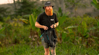 Russ Cook stood in nature wearing a bucket hat and huel tshirt
