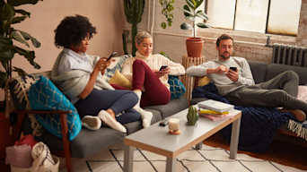 three people sat on sofas looking at their phones